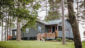 A two-story cabin with a porch, surrounded by trees. - Floating and Glamping at Big Piney River (Licking)
