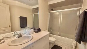A bathroom with a white sink, mirror, and toilet, a shower with a glass door, and a black bath mat. - Cozy One Bedroom Basement Apt with Free Parking (Markham)