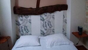 A bed with a wooden headboard, white bedding, and a patterned pillow. - House 8 sleeps 6 3 bedrooms (including mezzanine) (Ternant)