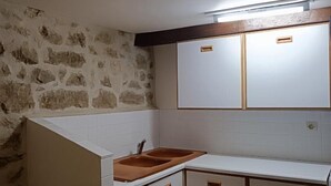 A compact kitchen with white cabinets, a wooden countertop, and a stone wall. - House 8 sleeps 6 3 bedrooms (including mezzanine) (Ternant)
