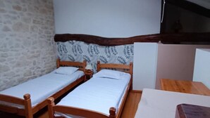 A small, cozy room with two wooden beds, a stone wall, and a sloped ceiling with a skylight. - House 8 sleeps 6 3 bedrooms (including mezzanine) (Ternant)