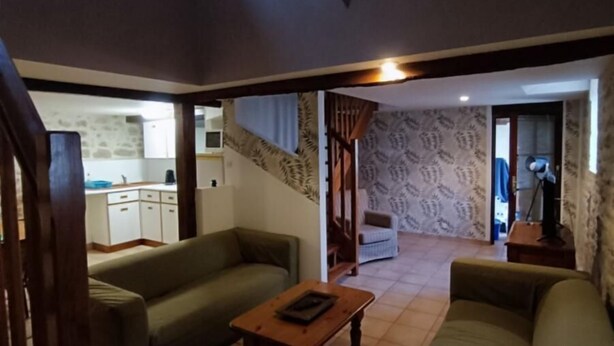 A spacious living area with a sofa, a coffee table, and a staircase leading to another level. - House 8 sleeps 6 3 bedrooms (including mezzanine) (Ternant)