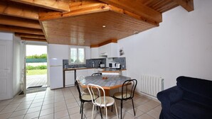 Een kleine keuken met een eettafel, stoelen en een donkergrijze bank.