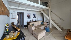 A spacious living area with a high ceiling, a staircase, a sofa, and a dining table. - Villa Kaz in Thomy, pool and Spa Panoramic sea view of Pointe Noire bay (Pointe-Noire)