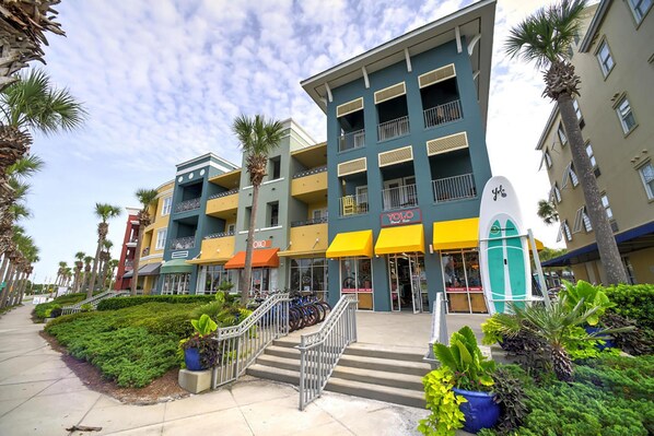 A multi-story building with balconies, a storefront, and a staircase leading to the entrance.