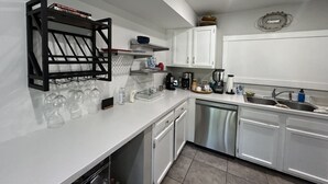 Une cuisine moderne avec des meubles blancs, un lave-vaisselle, un évier et un porte-bouteilles contenant plusieurs verres.