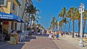Une promenade en bord de mer bordée de palmiers, un restaurant et une enseigne indiquant un restaurant de cuisine turque.