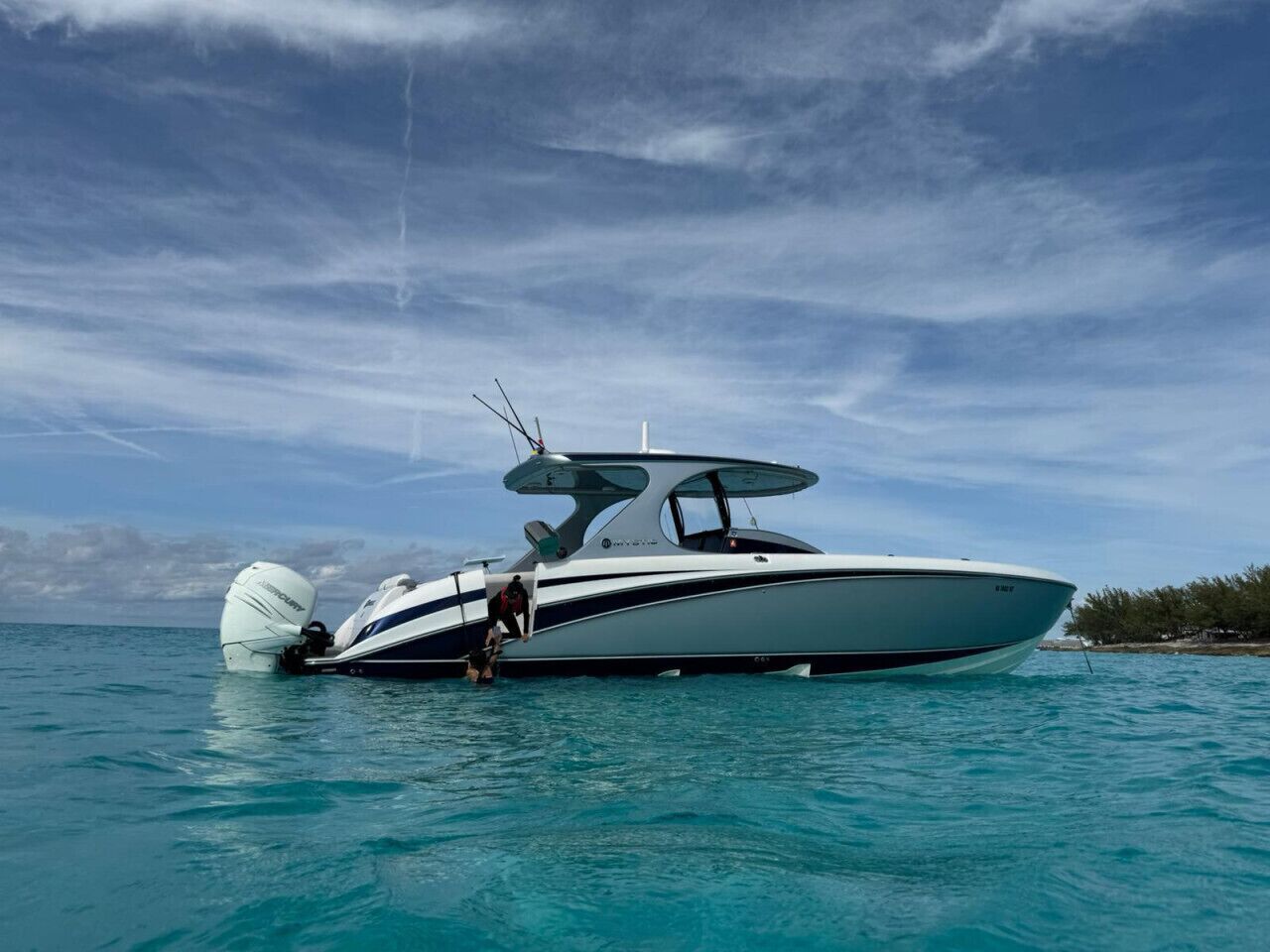 Un barco motor navegando en aguas turquesas tranquilas bajo un cielo despejado.
