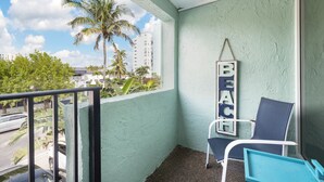 A balcony with a view of palm trees and buildings, a chair, and a 'BEACH' sign. - CasaDonna's Driftwood Retreat (Hollywood)