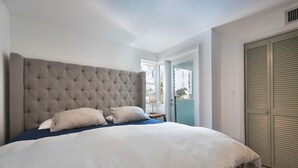 A bedroom with a large bed, a window, and a door. - CasaDonna's Driftwood Retreat (Hollywood)