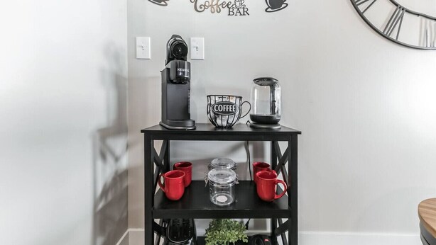 A black coffee station with a Keurig coffee maker, a coffee pot, and a coffee mug on a black shelf. - Walk to Bengals, Reds, Free Parking, King Bed, Gym (Cincinnati)
