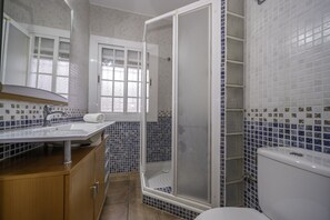 Ein Badezimmer mit Dusche, Toilette, Waschbecken und einem Fenster.