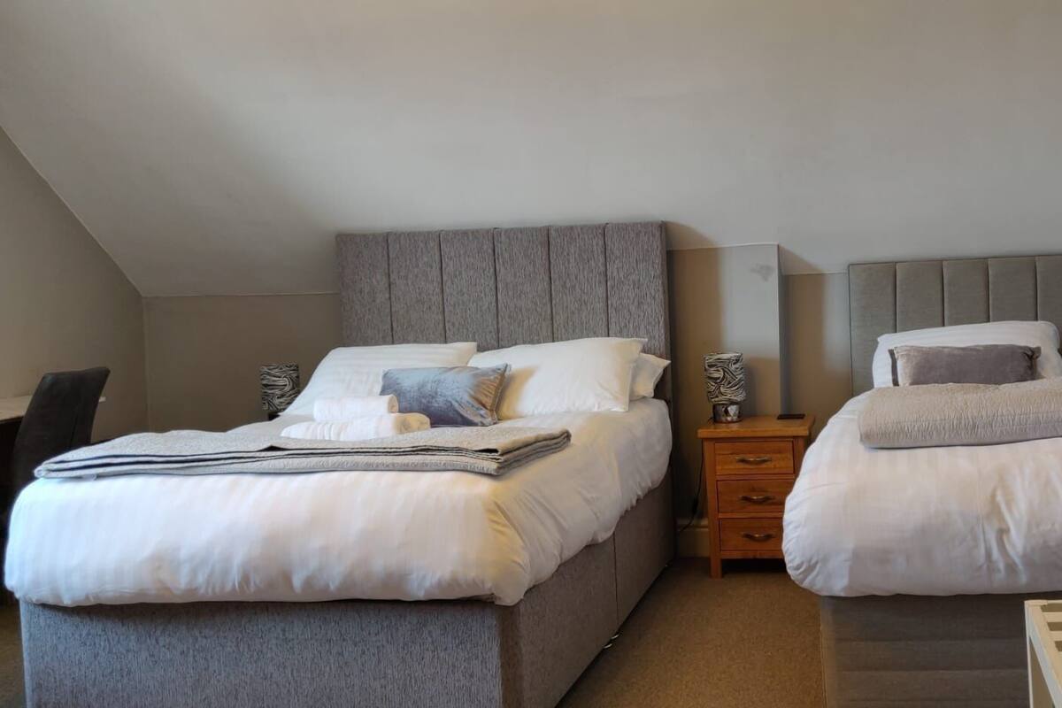 A bedroom with two beds, a desk, and a nightstand.