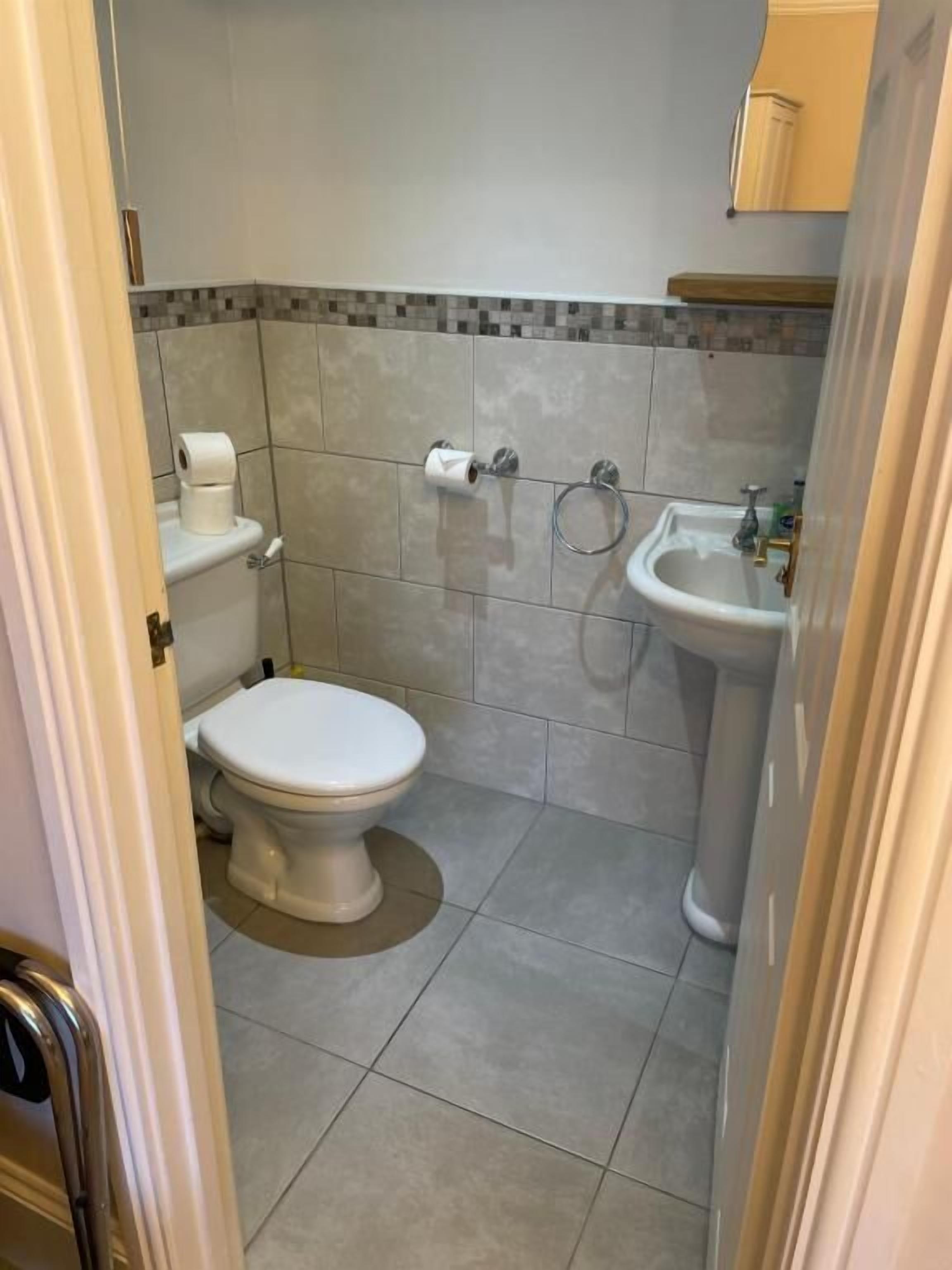 Un baño pequeño con inodoro, lavamanos y toallero.