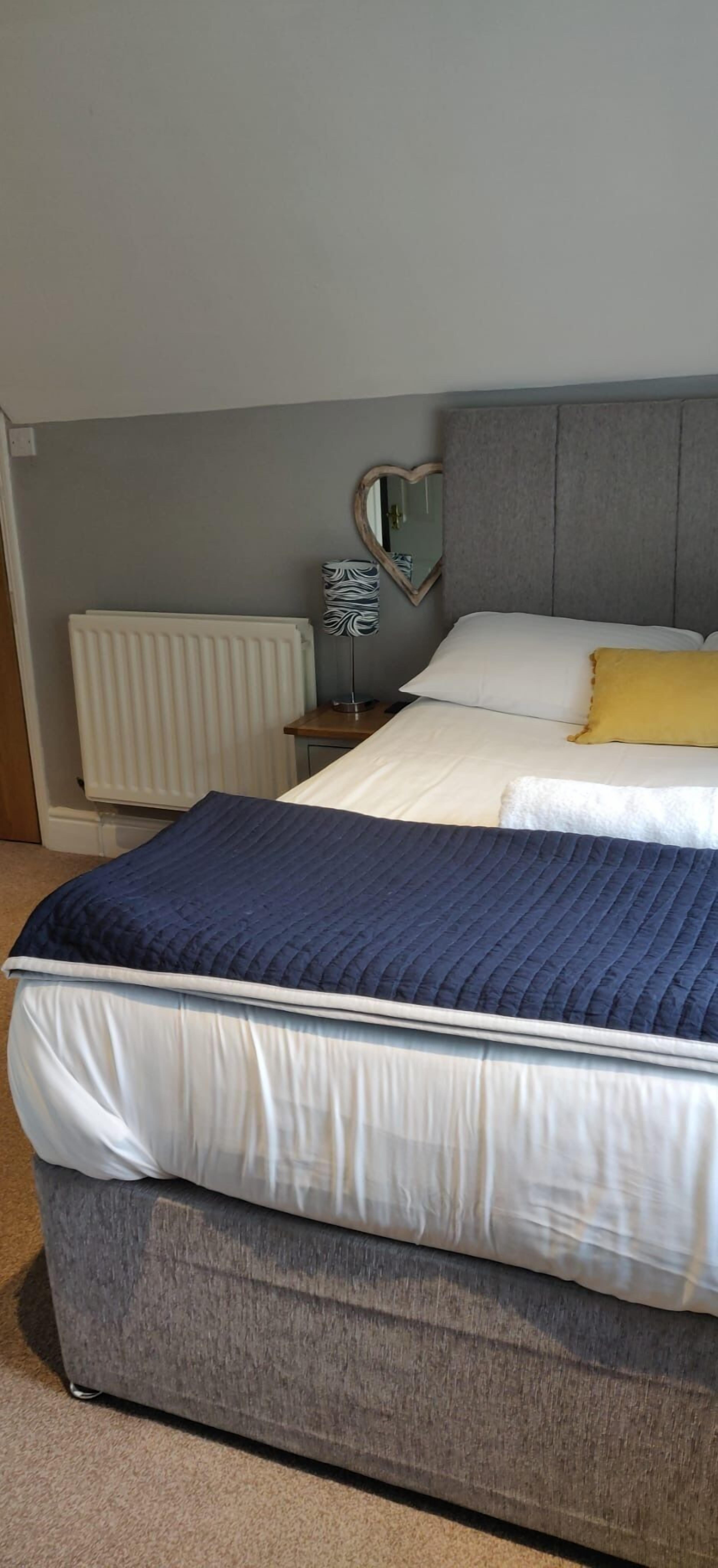 Ein Schlafzimmer mit einem Bett, einem Nachttisch, einem Spiegel und einer Heizung.
