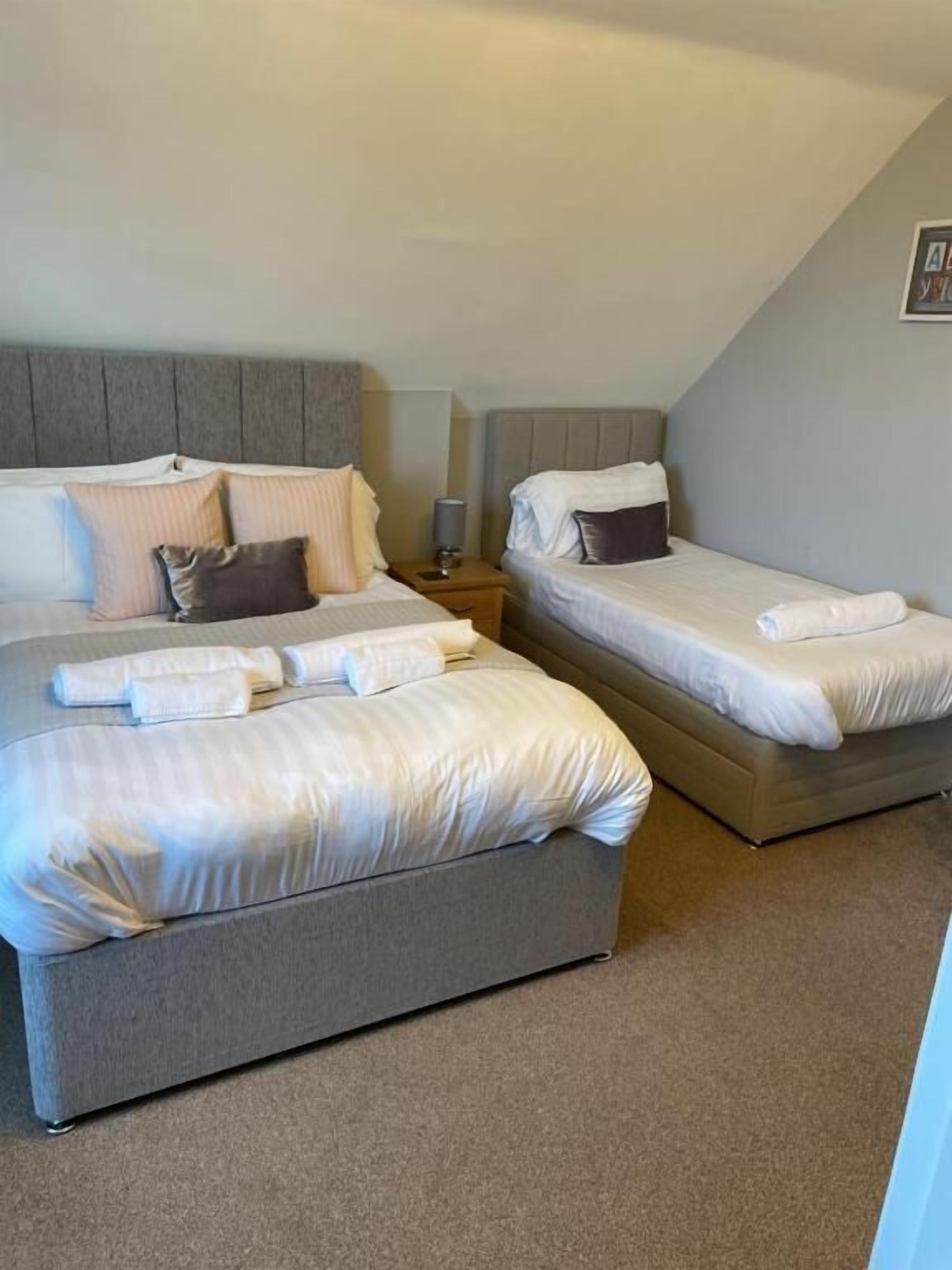 A hotel room with two beds, a nightstand, and a lamp.