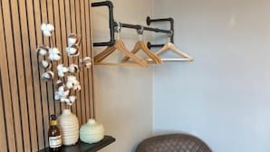 A corner room with a brown leather armchair, a wooden panel wall, a black pipe with wooden hangers, and decorative vases. - Bodalwyn Guest House (Aberystwyth)