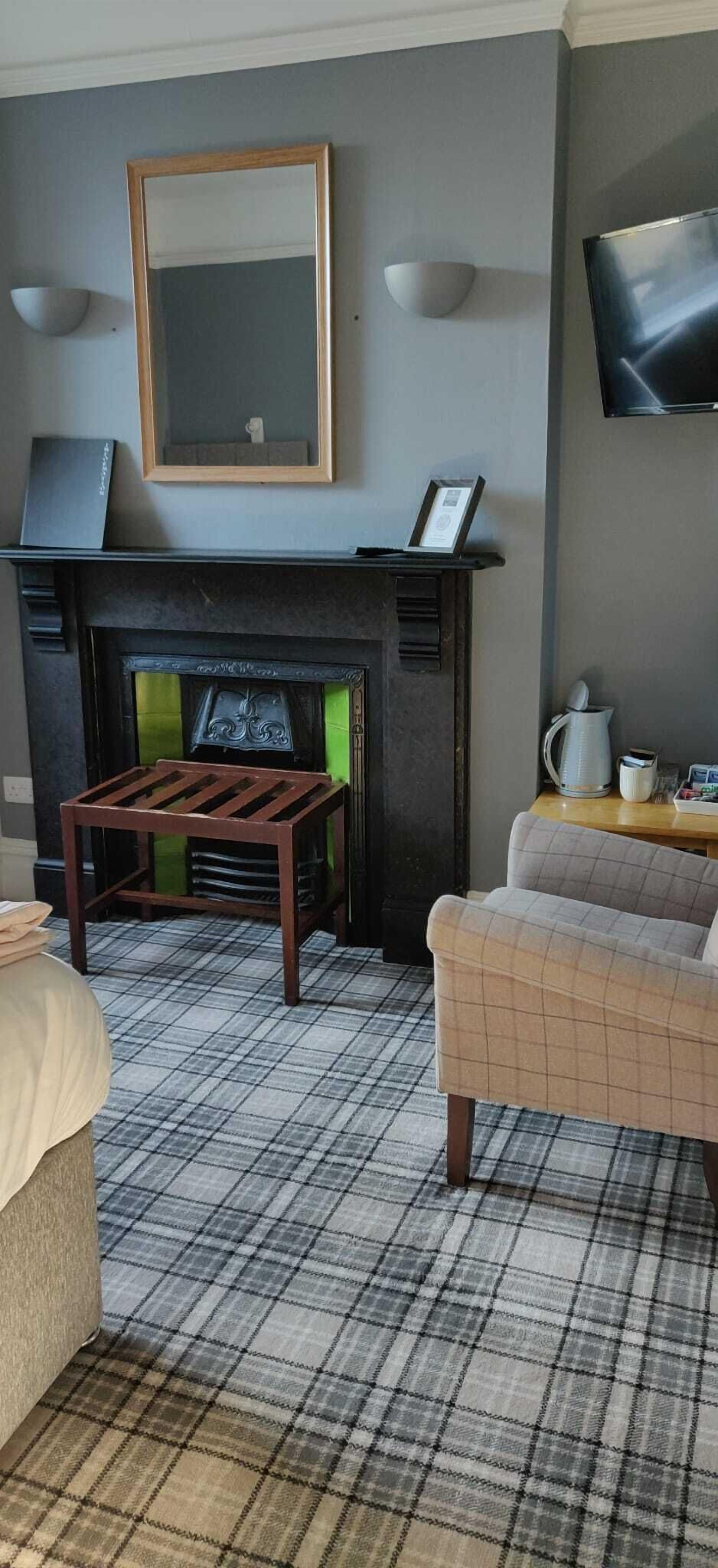 A living room with a fireplace, a sofa, a coffee table, and a television mounted on the wall.