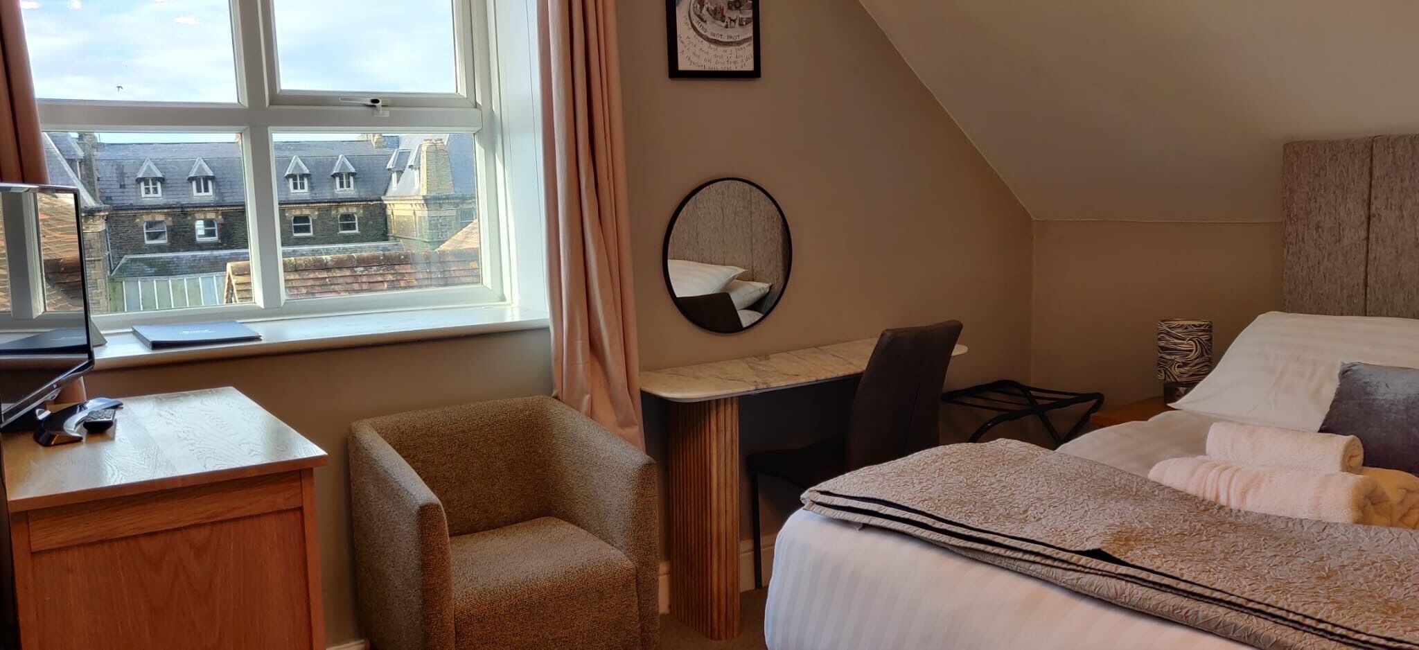 Une chambre d’hôtel équipée d’un bureau, d’une chaise et de deux lits.