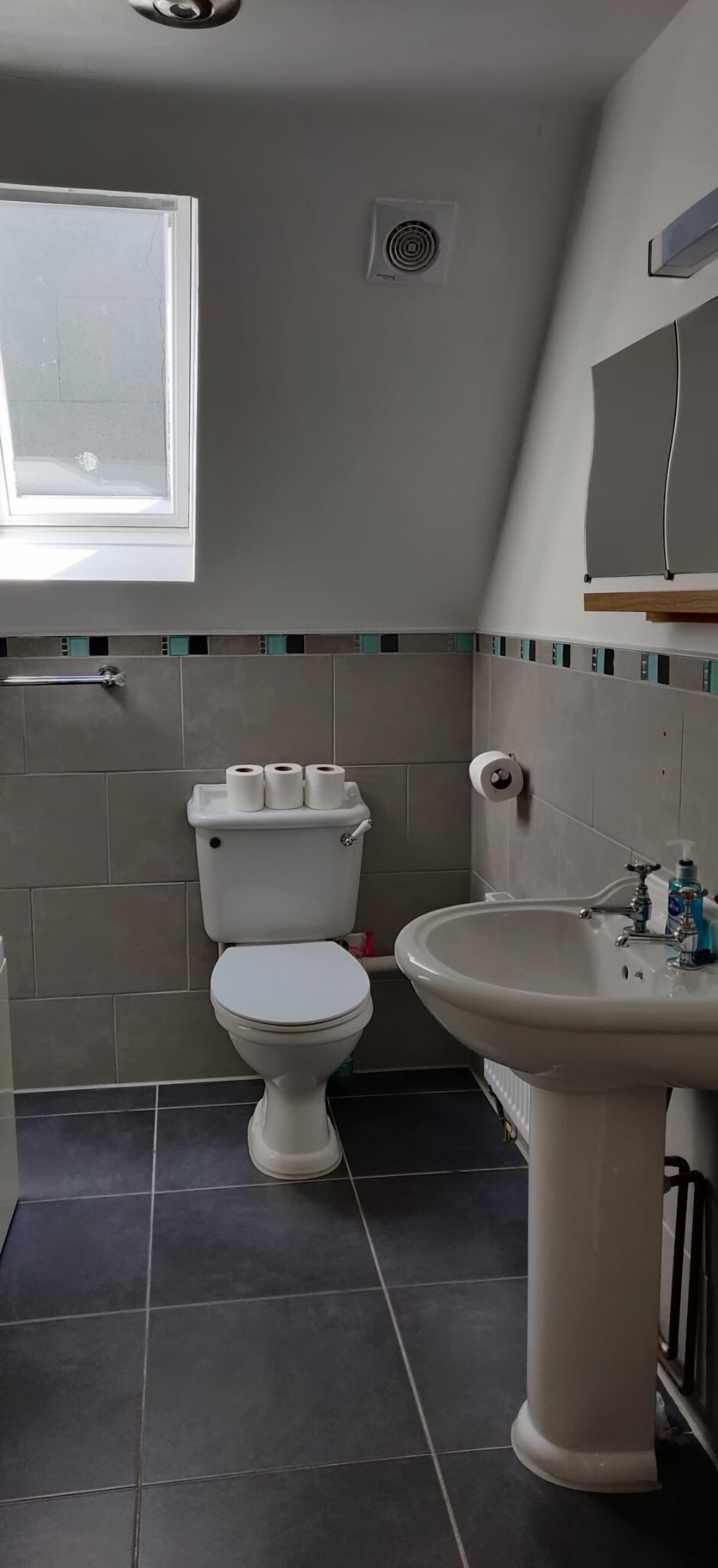 Ein Badezimmer mit Toilette, Waschbecken und Fenster.