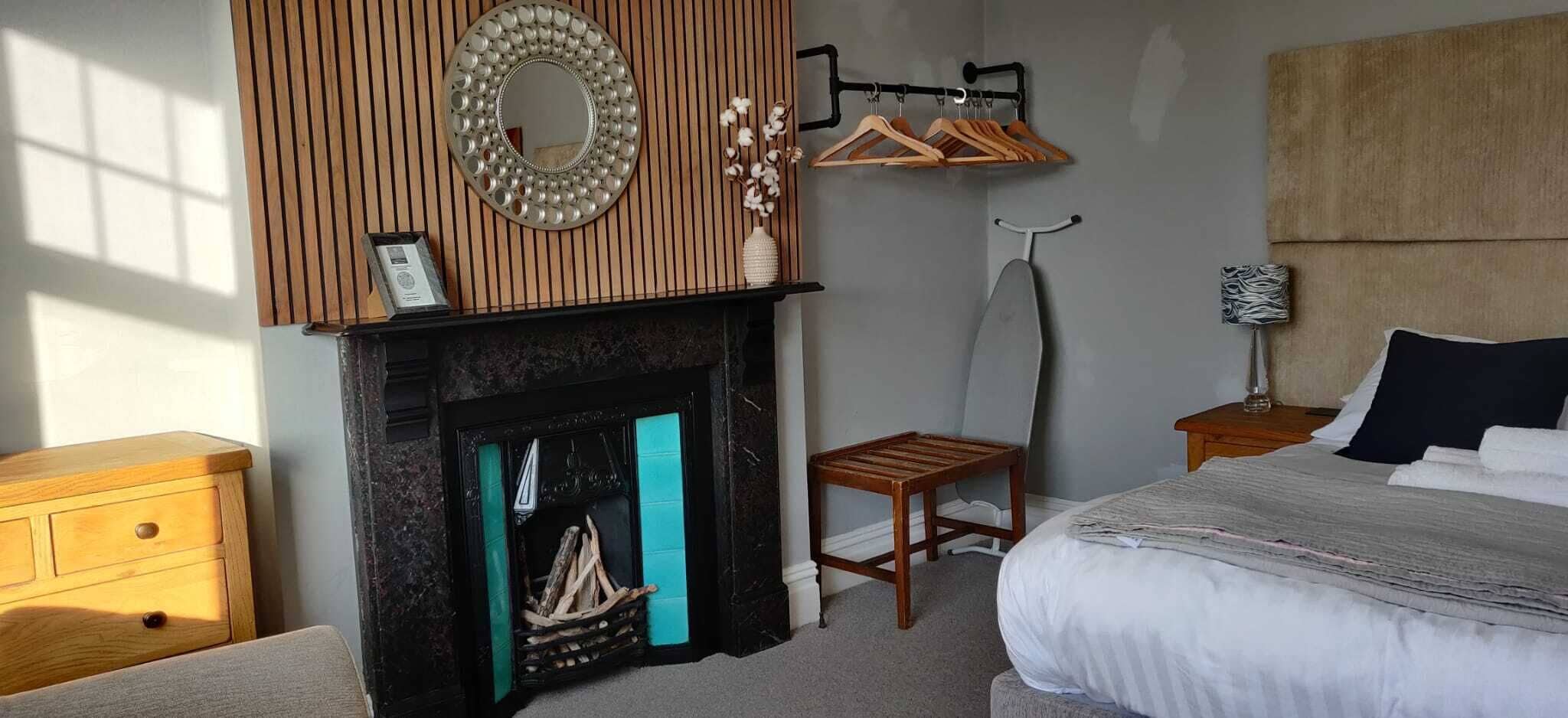 Une chambre à coucher avec une cheminée, des meubles en bois, un lit et un miroir fixé au mur.