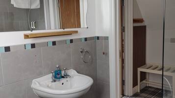 Een badkamer met een witte wastafel, een spiegel en een houten plank erboven.
