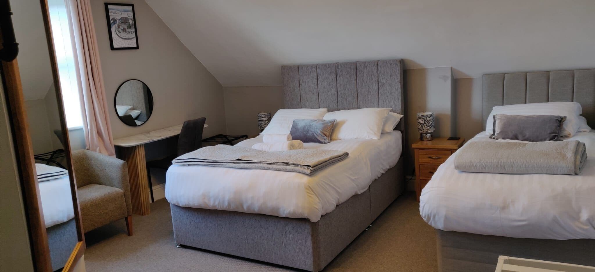 A bedroom with two beds, a desk, and a chair.