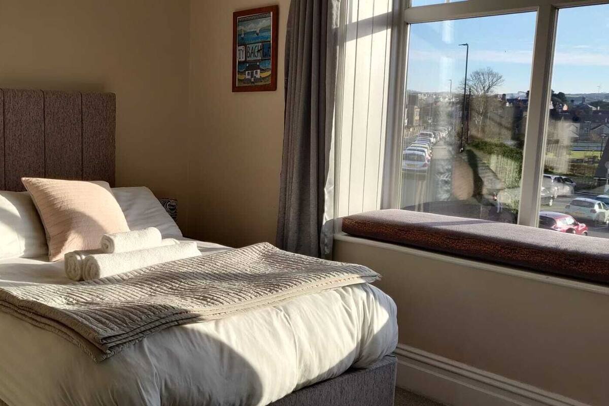 A neatly made bed with a headboard, pillows, and a blanket.