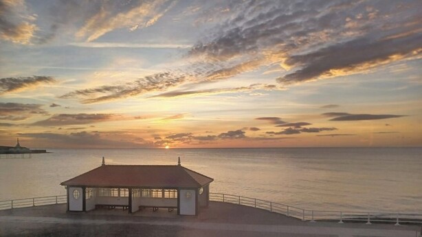 A coastal sunset view with a gazebo-like structure near the water. - Bodalwyn Guest House (Aberystwyth)