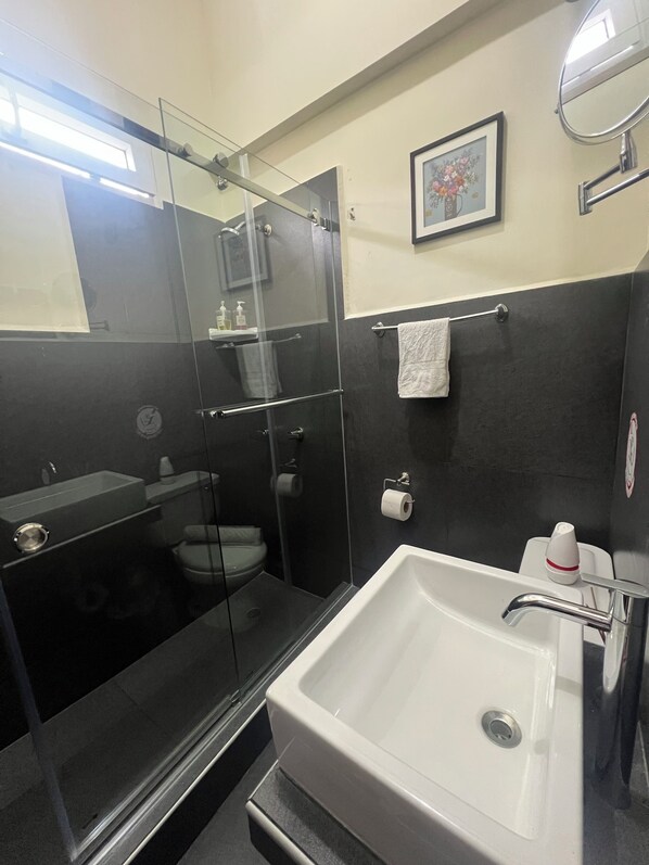 Ein modernes Badezimmer mit einer Duschkabine, einem weißen Waschbecken und einer Toilette.
