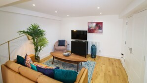 A living room with a sofa, coffee table, TV, and a potted plant. - London Gorgeous Two Bedroom Apartment (Mitcham Junction)