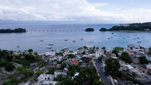 Un pueblo costero con un puerto deportivo, edificios y un puente.