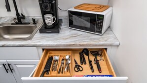 Eine Küche mit Mikrowelle, Kaffeemaschine und einer Schublade mit Besteck.