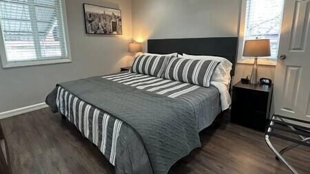 A bedroom with a large bed, a nightstand, a lamp, and a picture on the wall. - 2 King Beds | Near Sugar House & Downtown (South Salt Lake)
