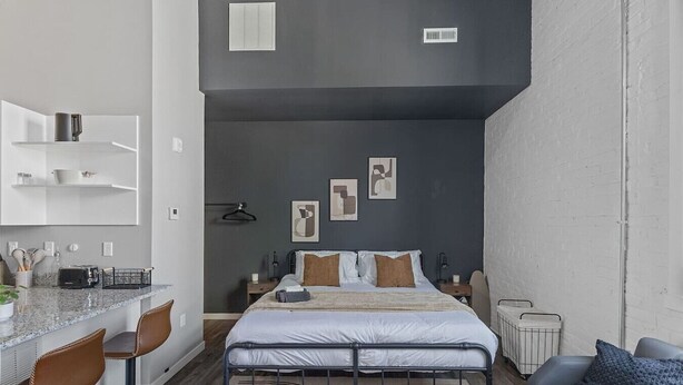 Un dormitorio moderno con cama, mesitas de noche, escritorio y sofá.