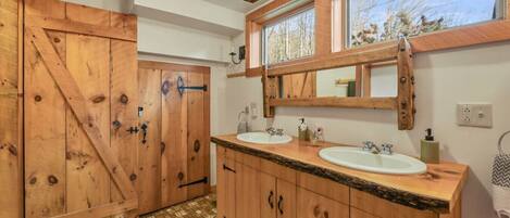 Une salle de bain en bois avec deux lavabos, un grand miroir et une fenêtre.