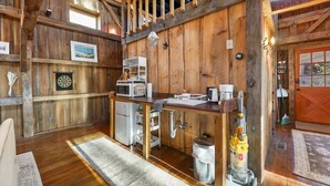 Interior rústico de madera con cocina que incluye un lavamanos, microondas y cafetera.