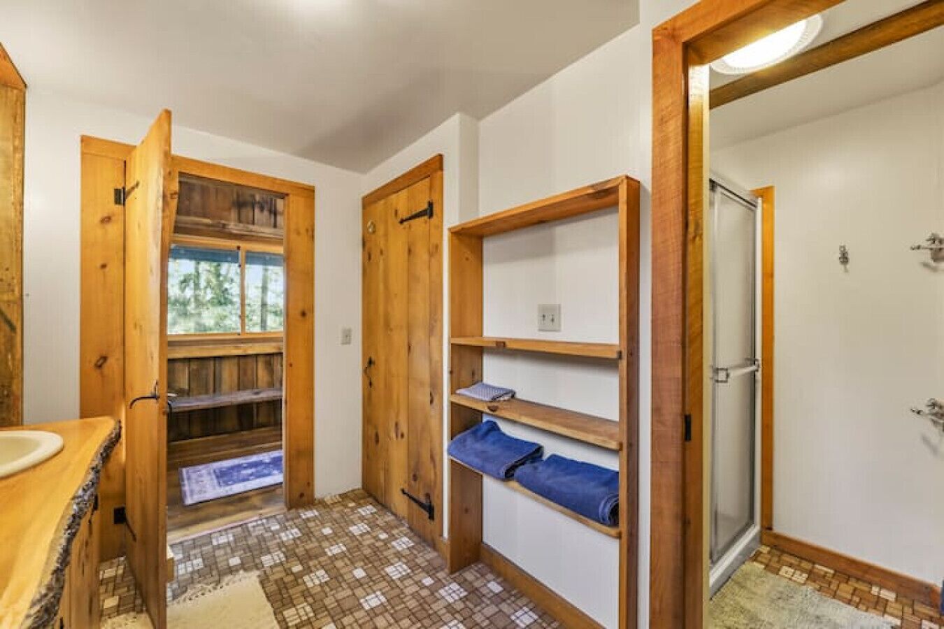 Un baño con estantes de madera, ducha y vistas al exterior.