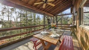 Una terraza de madera con una mesa lista para comer, con vistas a un bosque.