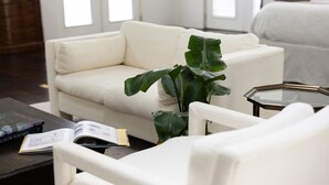 Ein modernes Wohnzimmer mit einem weißen Sofa, einem Couchtisch und einer großen Zimmerpflanze.