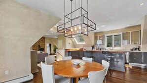 Eine moderne Küche mit einer zentralen Kochinsel, weißen Stühlen und einem Holztisch.