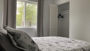 A bedroom with a bed, a window with curtains, and a wardrobe.