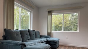 A modern living room with a sectional sofa, large windows, and hardwood flooring.
