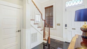 Una escalera con barandillas de madera y piso de baldosas negras que lleva a una puerta blanca.