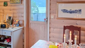 A cozy room with a wooden interior, a desk with a computer and books, a table with candles, and framed pictures on the walls. - Beach front home in Omastrand (Omastrand)