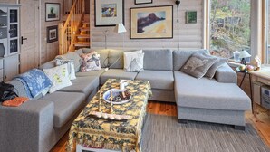 A cozy living room with a grey sectional sofa, a patterned coffee table, and a staircase leading to an upper level. - Beach front home in Omastrand (Omastrand)