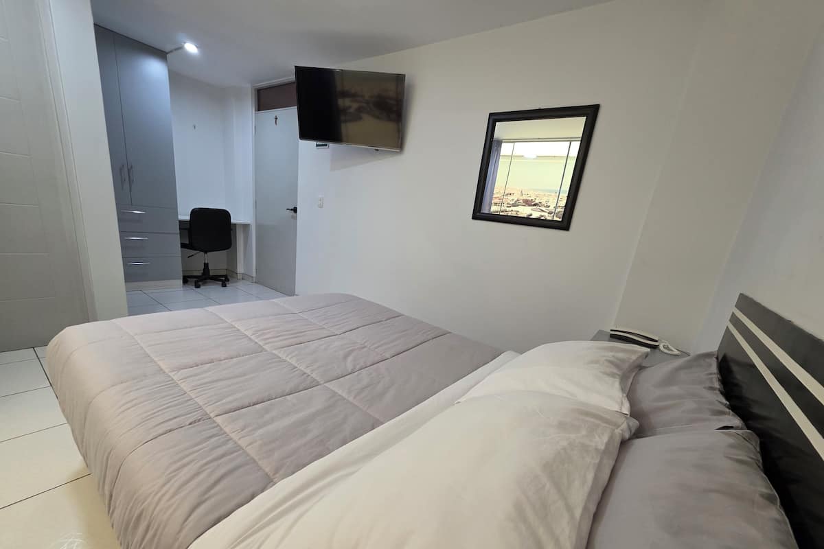 Ein Schlafzimmer mit einem Bett, einem an der Wand montierten Fernseher und einem Fenster mit Blick.