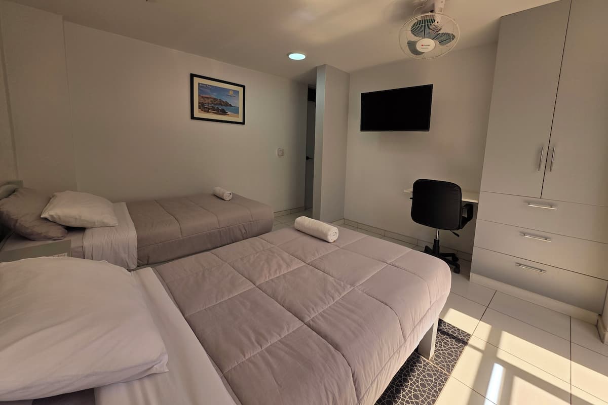 Ein Schlafzimmer mit zwei Betten, einem an der Wand montierten Fernseher und einem Kleiderschrank.