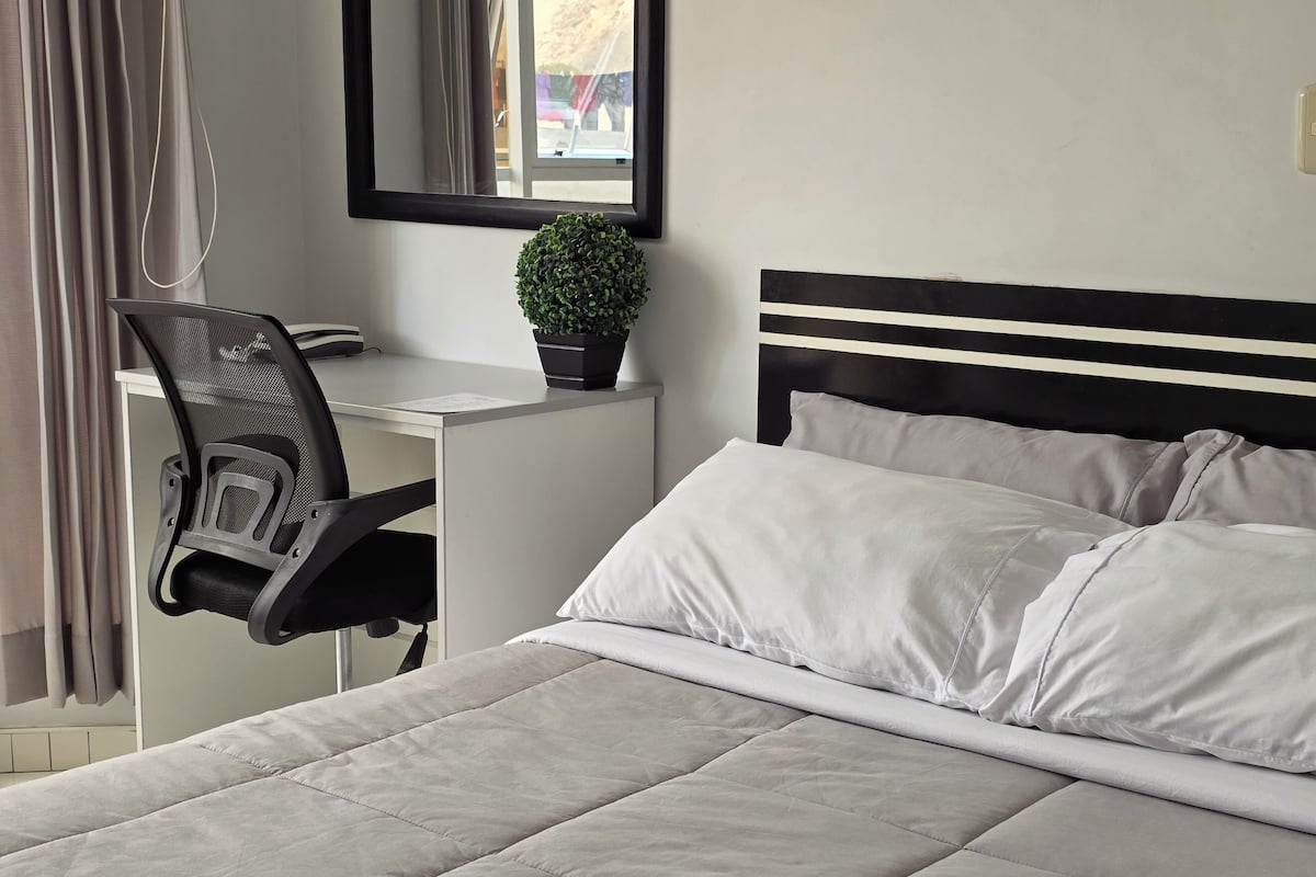 Ein ordentlich eingerichtetes Schlafzimmer mit Bett, Schreibtisch und Stuhl.