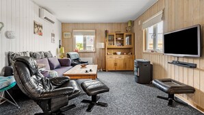 Un salon chaleureux avec un canapé en cuir, une table basse et un téléviseur fixé au mur.